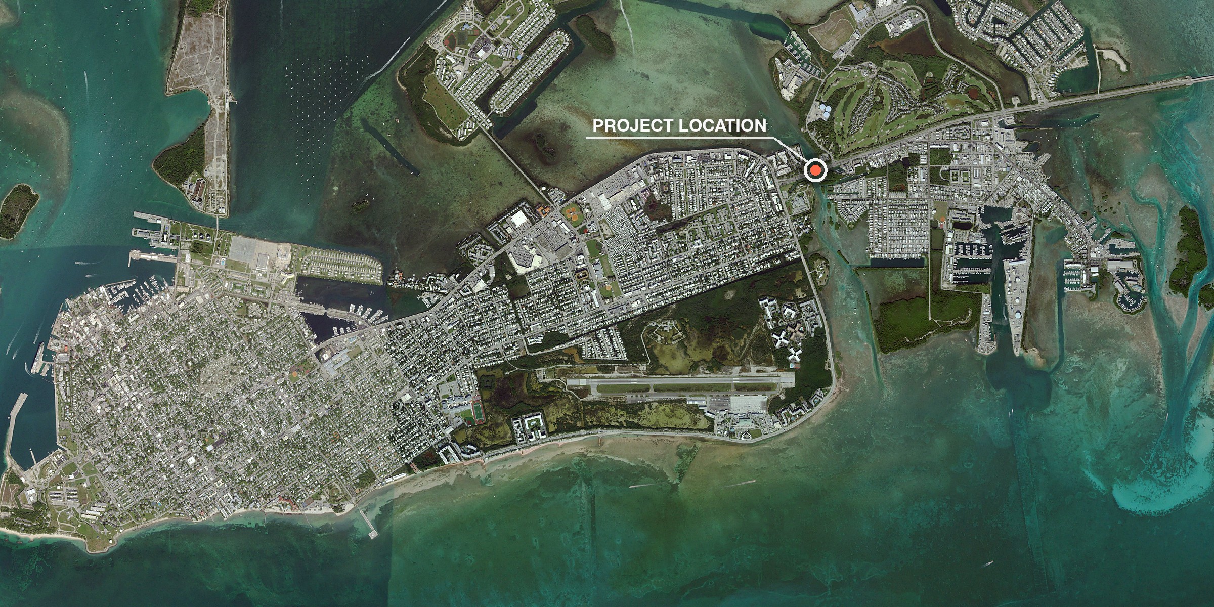 Aerial view of the whole island of Key West ringed by turquoise flats, with Old Town at lower left and the airport along the south shore, and a marker labeled Project Location at the upper right where US 1 crosses Cow Key Channel onto the island.