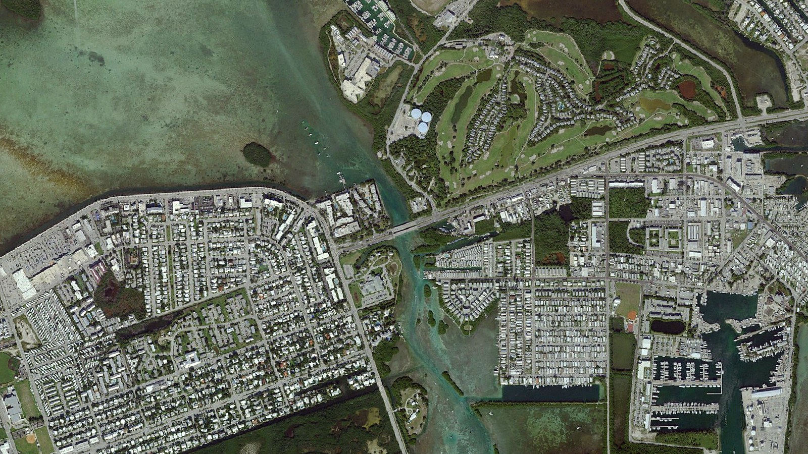 Aerial view of the gateway to Key West: US 1 crossing Cow Key Channel onto the island, with the marina and Stock Island to the east and the flats to the north.