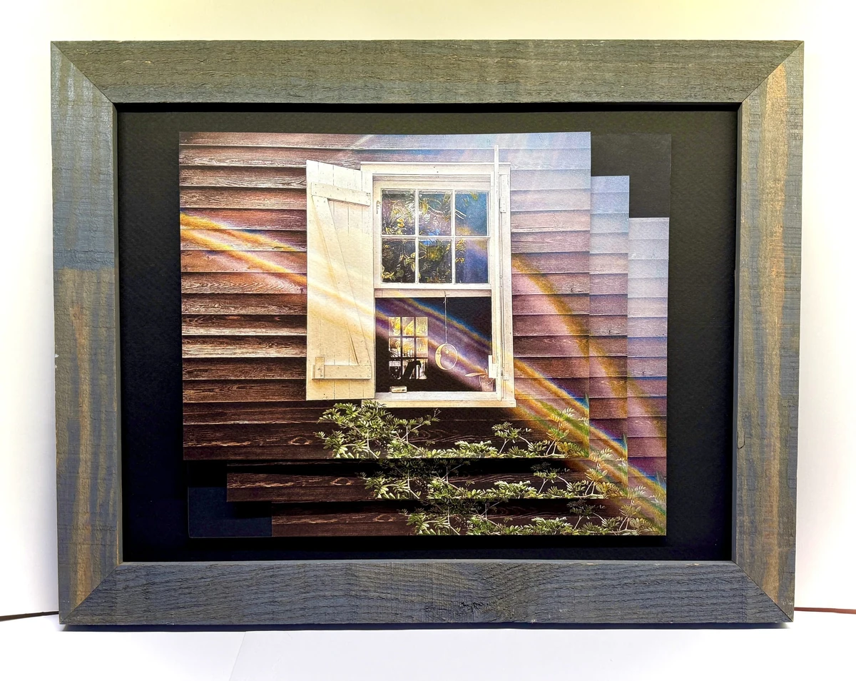 Framed pieced photograph, the panels stepped and offset, of a white shuttered window on weathered clapboard siding crossed by a rainbow of light