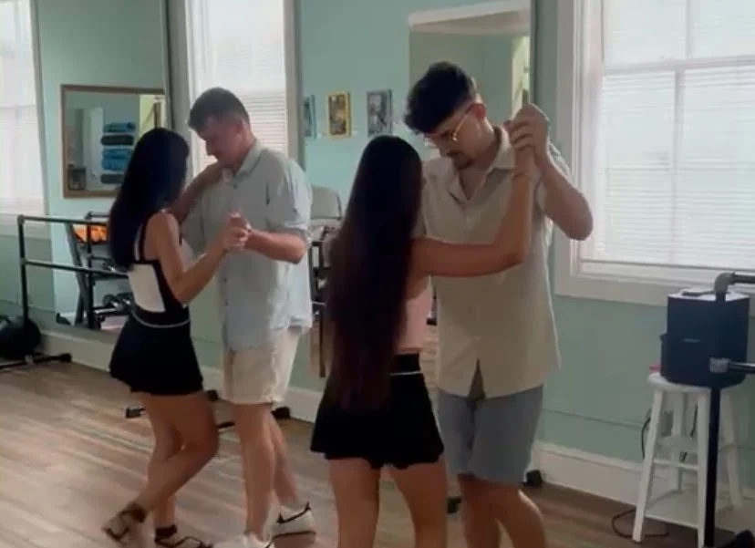 Two couples practicing partner dance in closed hold in a mirrored Key West studio during a Dance Key West group class