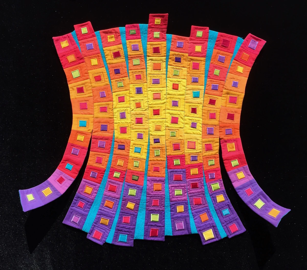 "Swingin' Squares," 36 x 33 x 2 inch shaped art quilt in red, orange, yellow and purple with appliqued squares, wired lower edges curling outward, photographed on black
