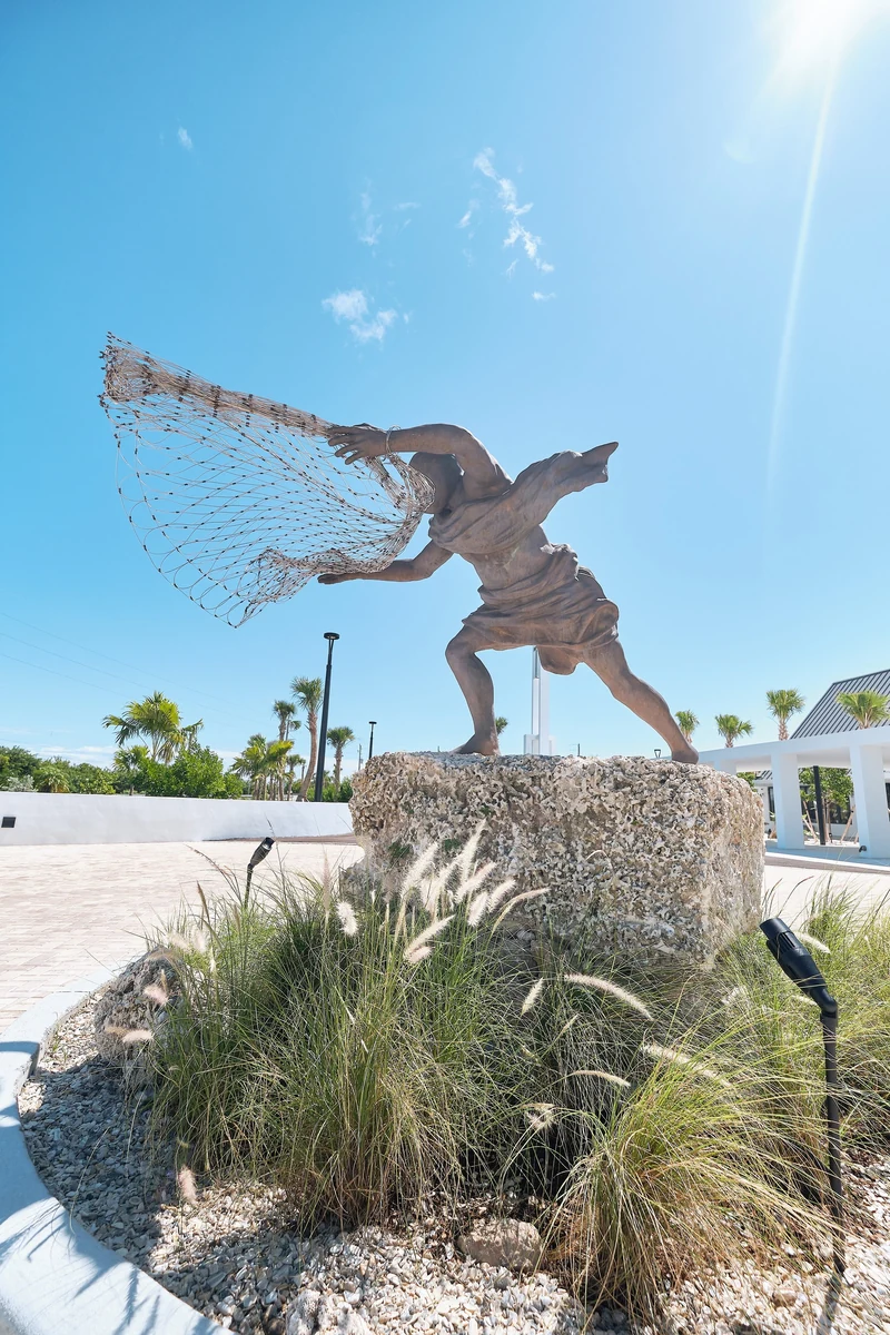 The Fisherman, 2021, life-size bronze figure casting a stainless steel and copper net, on an oolite boulder base at Saint Peter the Fisherman Catholic Church, Big Pine Key