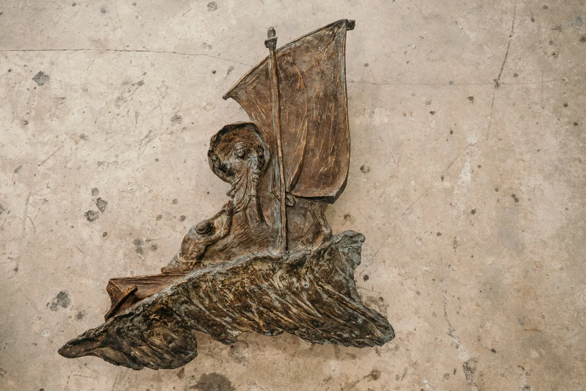 Bronze relief from the diptych Miraculous Catch and Take Courage, 2020, a sailing boat with a figure at the tiller, mounted on a concrete wall