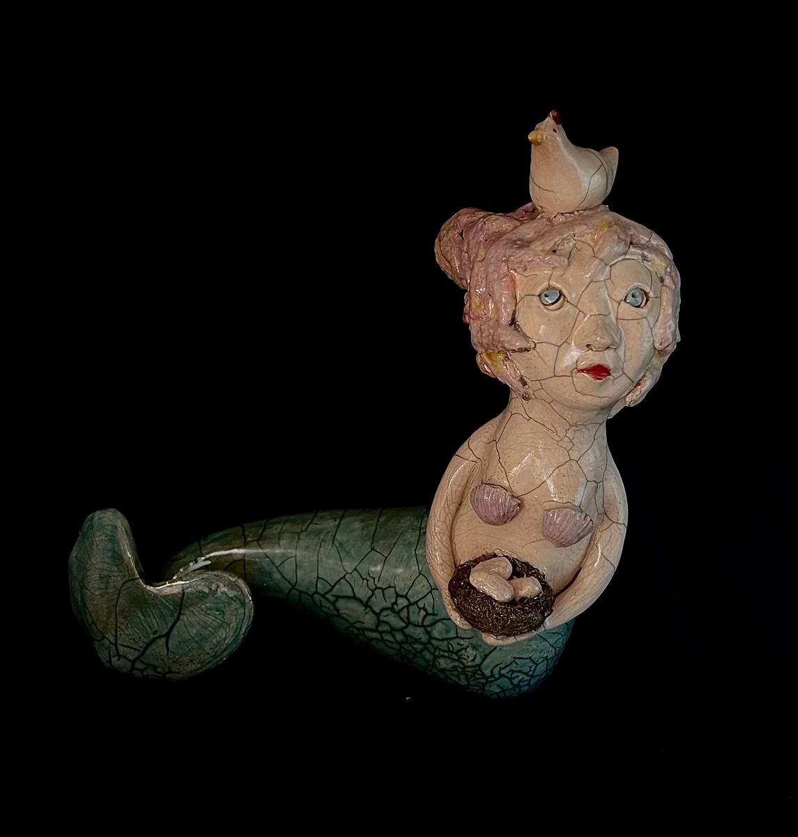 "Warm hands", Raku ceramic mermaid sculpture holding a nest of eggs with a small bird perched on her head