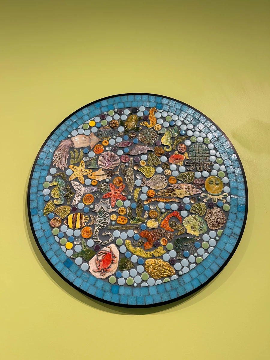 Textures of the Tide, a circular ceramic and glass mosaic of sea creatures by Sonata Kazimieraitiene, built from clay pieces hand-sculpted by Ocean Exploration Center visitors, on 
