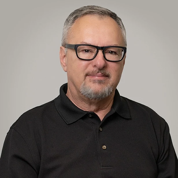 Tim Boatright, head-and-shoulders portrait in a black polo shirt and dark-framed glasses against a plain gray backdrop